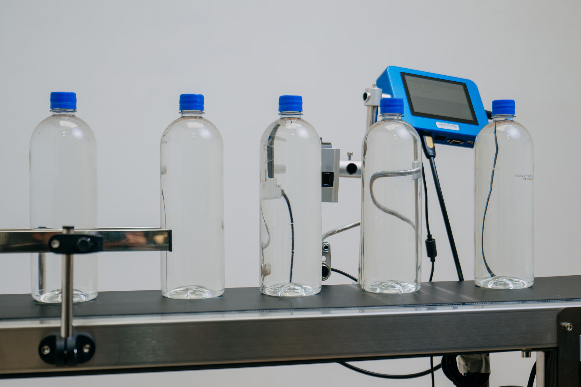 Codificadora TIJ automática imprimiendo sobre botellas en banda transportadora